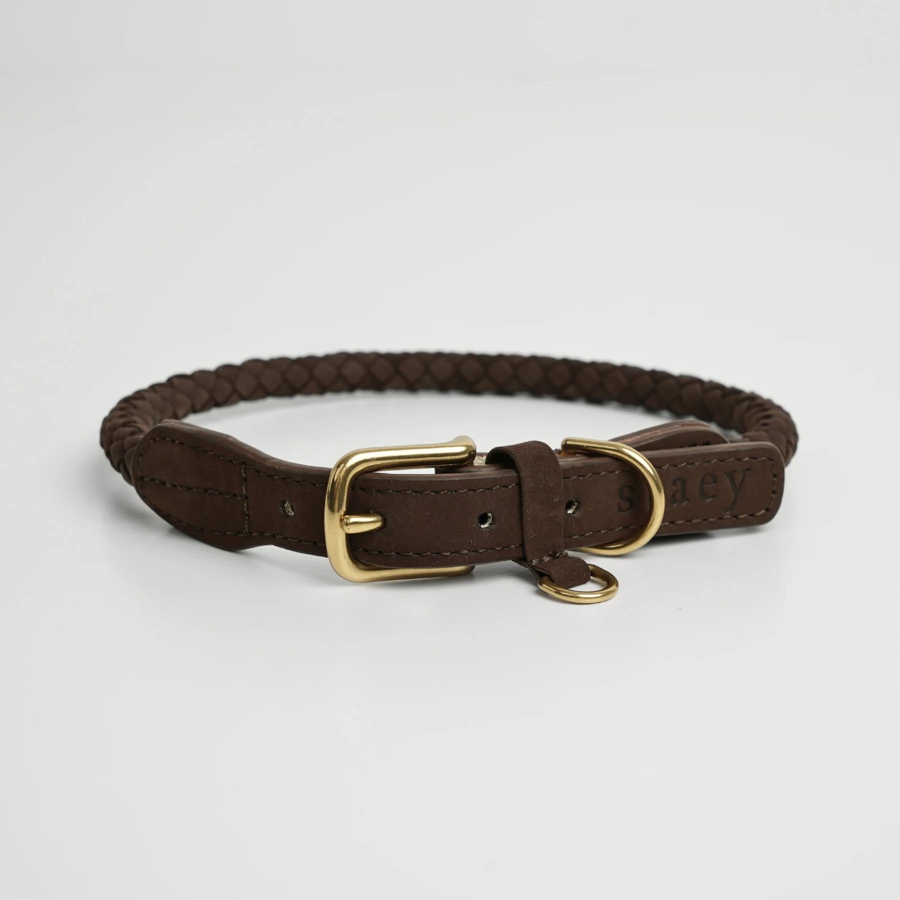 Brown braided leather dog collar with gold buckle on a light gray background