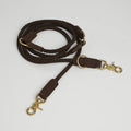 Brown braided leather dog leash with gold hardware on a light gray background