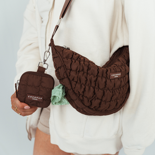Brown quilted bag and small pouch held by a person against a light background
