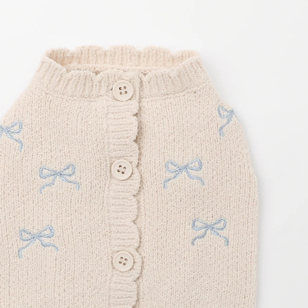 Knitted dog cardigan with button details and blue bow patterns on a white background